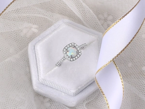 Detailed view of an opal engagement ring with a zircon halo in a white velvet box