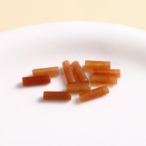 Macro shot of translucent orange agate beads with natural textures in a white dish