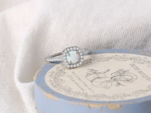 Macro shot of silver halo ring with round opal center and shimmering cubic zirconia pavé