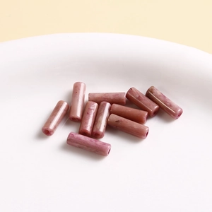Detailed view of pink-purple natural stone cylindrical beads with marble texture for DIY