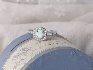 Macro shot of white opal engagement ring with pavé diamonds on a light blue gift box