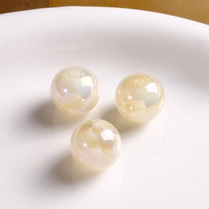 Macro view of three baroque iridescent round acrylic beads on a white ceramic surface