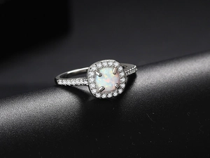 Macro shot of silver opal engagement ring with a halo of sparkling white zircons