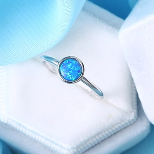 Minimalist silver ring with blue round opal in bezel setting on blue satin