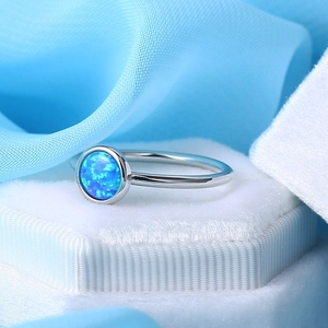 Elegant silver opal ring with round blue gemstone on a soft blue silk background