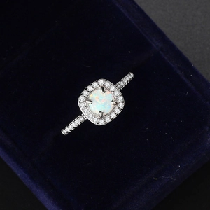 Classic silver-plated white opal engagement ring with cubic zirconia on blue velvet