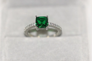 Vue rapprochée d'une bague argentée avec pierre verte carrée et micro-pavage de zircons fins