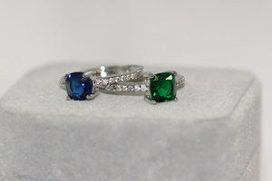 Gros plan de bagues en zircon bleu et vert taille coussin avec pavé en argent