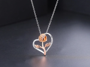 Detailaufnahme des Herzanhängers mit roségoldener Rose und funkelnden Zirkonia-Steinen
