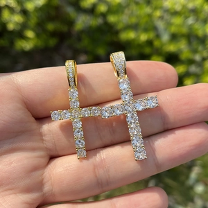 Hip hop kruishanger in goudkleur met 4mm zirkonia stenen vastgehouden in de hand