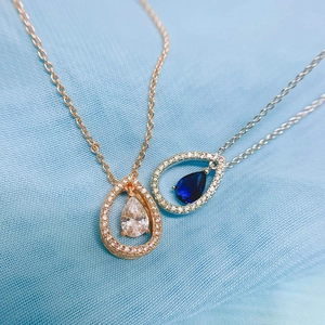 Primo piano di collane con pendente a goccia in zircone oro rosa e argento su tessuto
