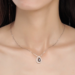 Collana a goccia placcata oro con pietra blu e halo di zirconi indossata da modella