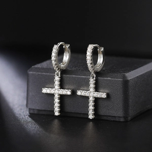 Macro shot of silver cross hoop earrings with white zircon pave setting on black velvet