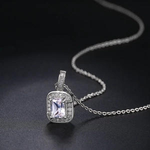 Macro shot of rectangular white zircon pendant with halo setting on a silver chain