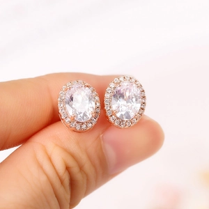 Dettaglio di orecchini halo in oro rosa con grandi pietre di zircone ovali
