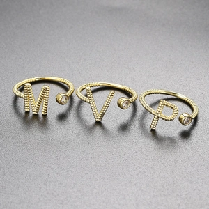 Detailansicht goldener verstellbarer Buchstabenringe mit Zirkonia und Kordelstruktur