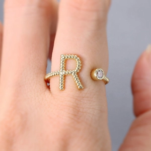 Details des verstellbaren Goldrings mit funkelndem Buchstaben R und Kristallstein