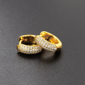 Macro detail of gold-plated huggie earrings featuring micro-pave white zircon stones