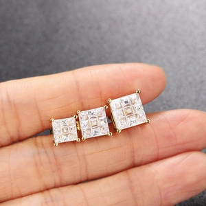Golden square zircon stud earrings set in three sizes shown on a fingertip for scale
