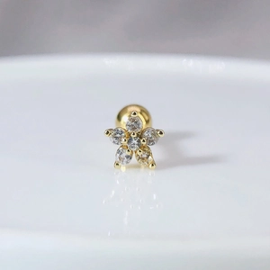 Détail macro d'un clou d'oreille fleur doré avec zircons et fermoir à vis boule