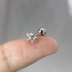 Vue macro d'un petit piercing fleur en argent avec zircons sur le bout d'un doigt