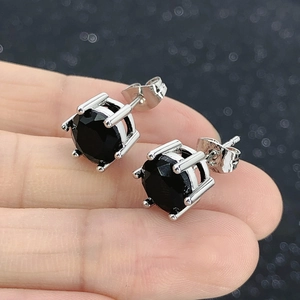 Macro view of classic round black zircon stud earrings with four-prong silver setting