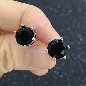 Close-up of classic silver four-prong round black zircon stud earrings for men