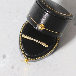 Detailed close-up of a gold-plated wavy ring with micro-pave zircons on black leather