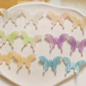 Close-up of colorful iridescent acetate butterfly charms with 3D marble texture in a tray