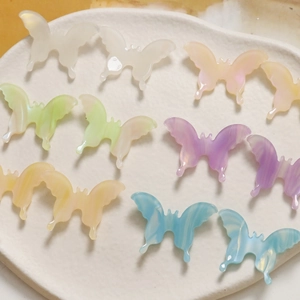 Detailed macro of 3D gradient acetate butterfly charms in assorted macaron pastel colors