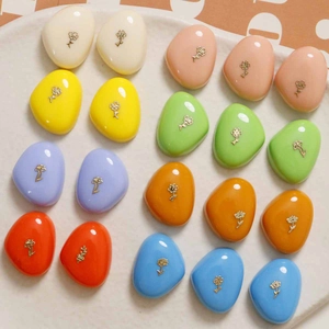Gros plan de charms en résine colorée avec petites fleurs dorées dans une assiette blanche