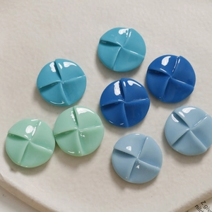 Close-up of 20mm round windmill-shaped resin buttons in four cool blue and green tones