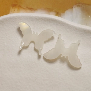 Macro view of creamy white 3D butterfly acetate charms with pearlescent finish
