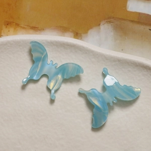 Detailed view of blue gradient acetate butterfly charms with 3D marble texture on ceramic