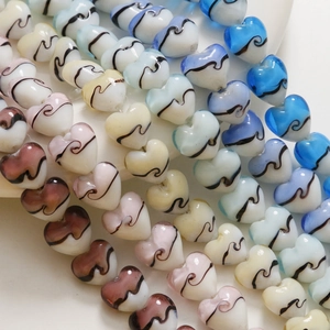 Vue macro de perles en verre de 15 mm en forme de cœur avec motifs rayés colorés