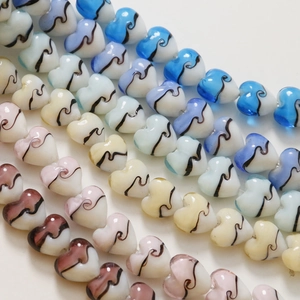 Vue macro de perles en verre en forme de cœur de 15 mm avec motifs à rayures colorées pour DIY