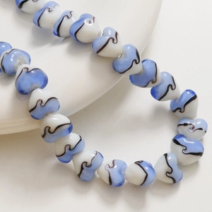 Vue rapprochée de perles cœur de 15mm rayées bleu et blanc avec lignes ondulées