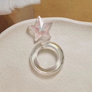 Close-up of iridescent acrylic round ring and star glitter charms for DIY jewelry making