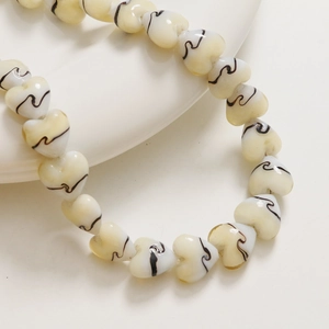 Vue macro de perles en verre en forme de cœur de 15mm avec motifs spirales pour bijoux DIY