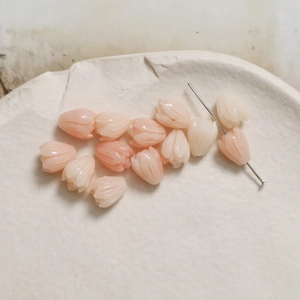 Macro shot of pink and white tulip resin beads on a textured stone tray for DIY jewelry