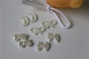 Detailed view of white pearl resin charms featuring stars and bows for DIY nail art and shoes