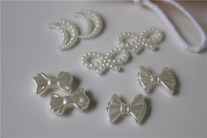 Close-up of pearl bow and crescent moon charms for DIY jewelry and shoe decoration