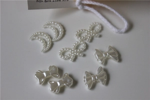 Detail view of pearl moon and resin bow accessories for DIY jewelry and shoe charms