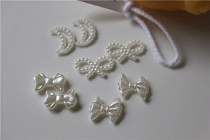 Macro shot of cream white resin charms featuring pearl moon and bow designs for DIY crafts
