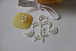 Macro detail of crescent moon pearl charms for DIY nail art and shoe accessories