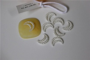 Macro detail of crescent moon charm crafted from white faux pearls for DIY jewelry crafts