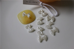 Macro shot of 9 pearl white bow-shaped charms for nail art and DIY shoe accessories