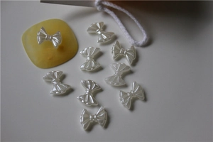Close-up of pearl white bow-shaped DIY charms with textured resin finish and elegant sheen