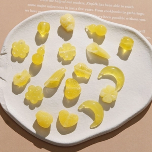 Macro detail of yellow resin charms in heart, moon, and flower shapes for DIY jewelry