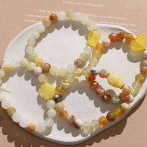 Ethnic resin beaded bracelets featuring moon and heart charms on a ceramic plate